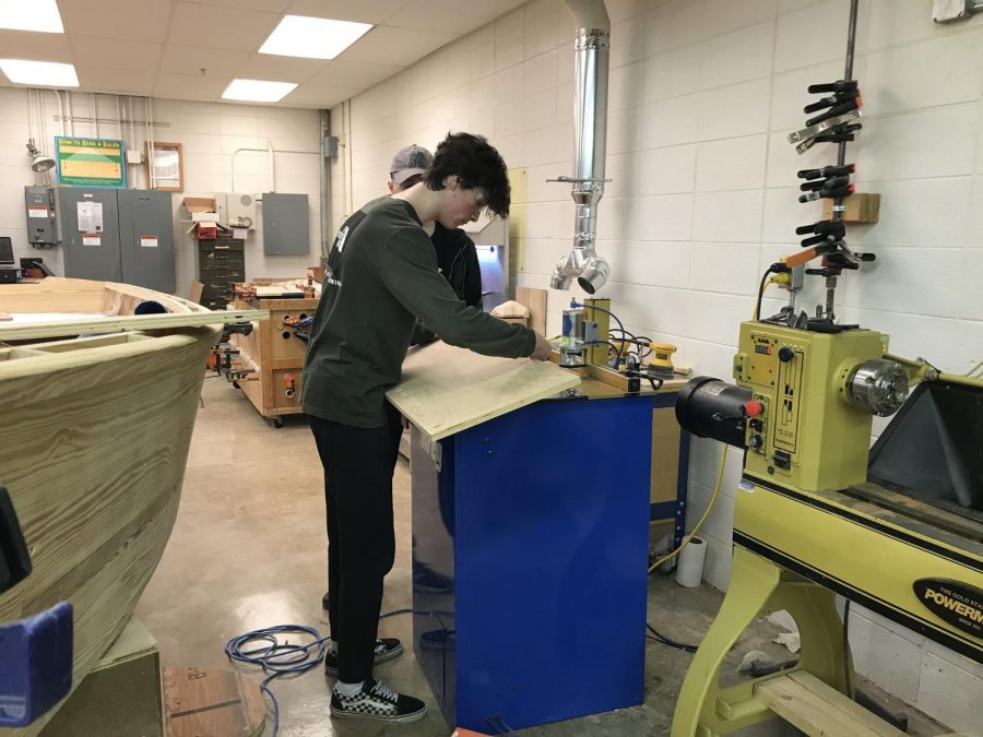 Senior Dylan Barrett works in the woodshop to cut holes for the newspaper stand project the club has taken on. 