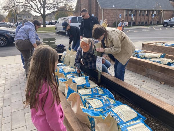 Senior Aidan Miller works with volunteers to secure birdhouses to the finished garden beds before filling them with soil. Photo by Heather Miller.