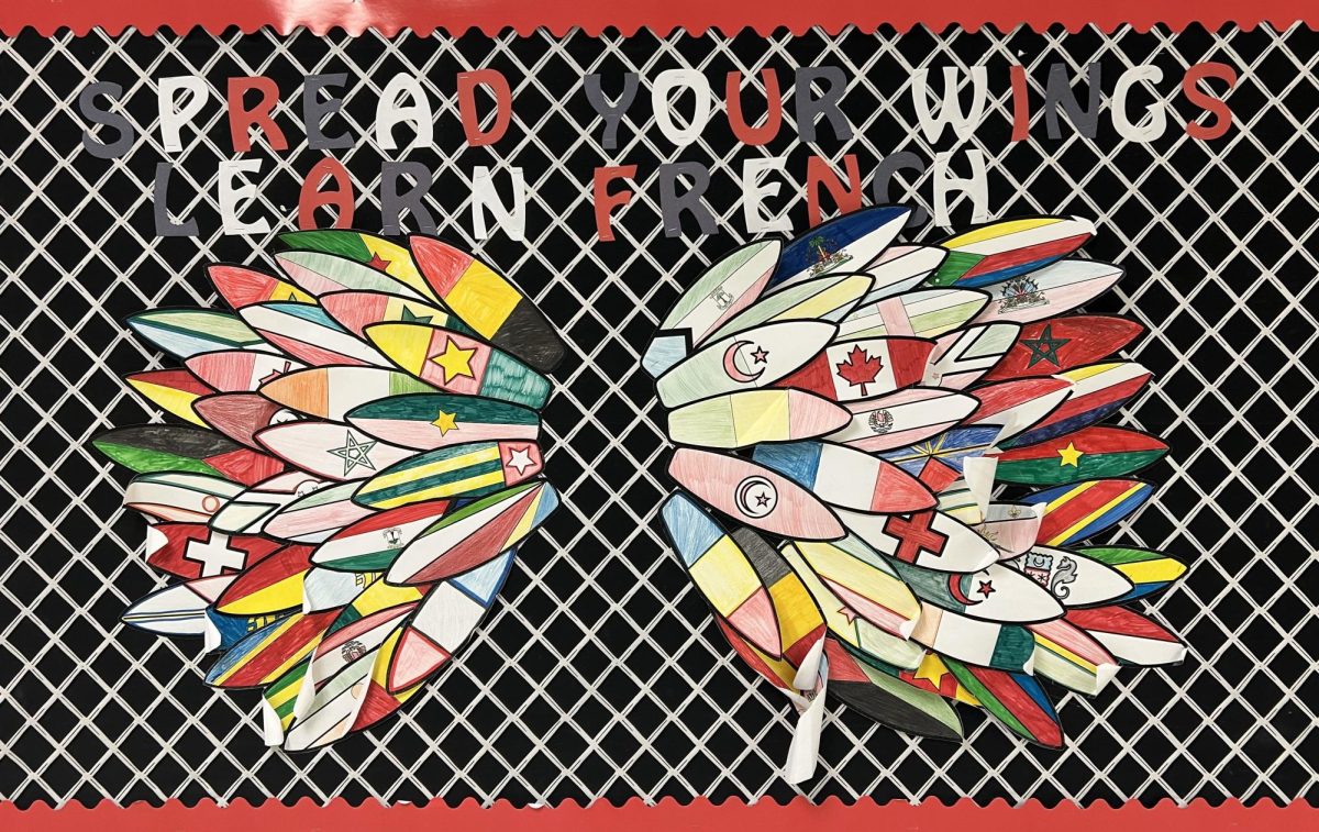 A bulletin outside a high school French classroom reads, "Spread Your Wings Learn French." Photo by Arjun Patel.