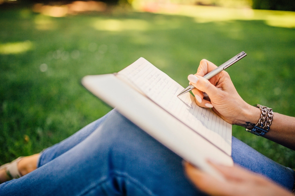A person writing in a notebook. Photo courtesy of Enchanted Pixie.