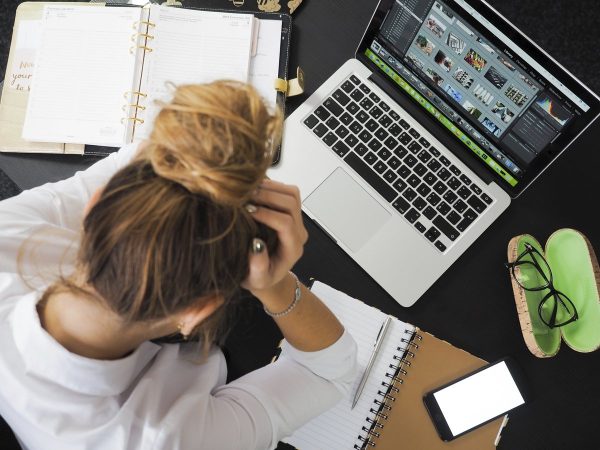 A person is stressed out as she works at her laptop. Photo courtesy of Raw Pixel.